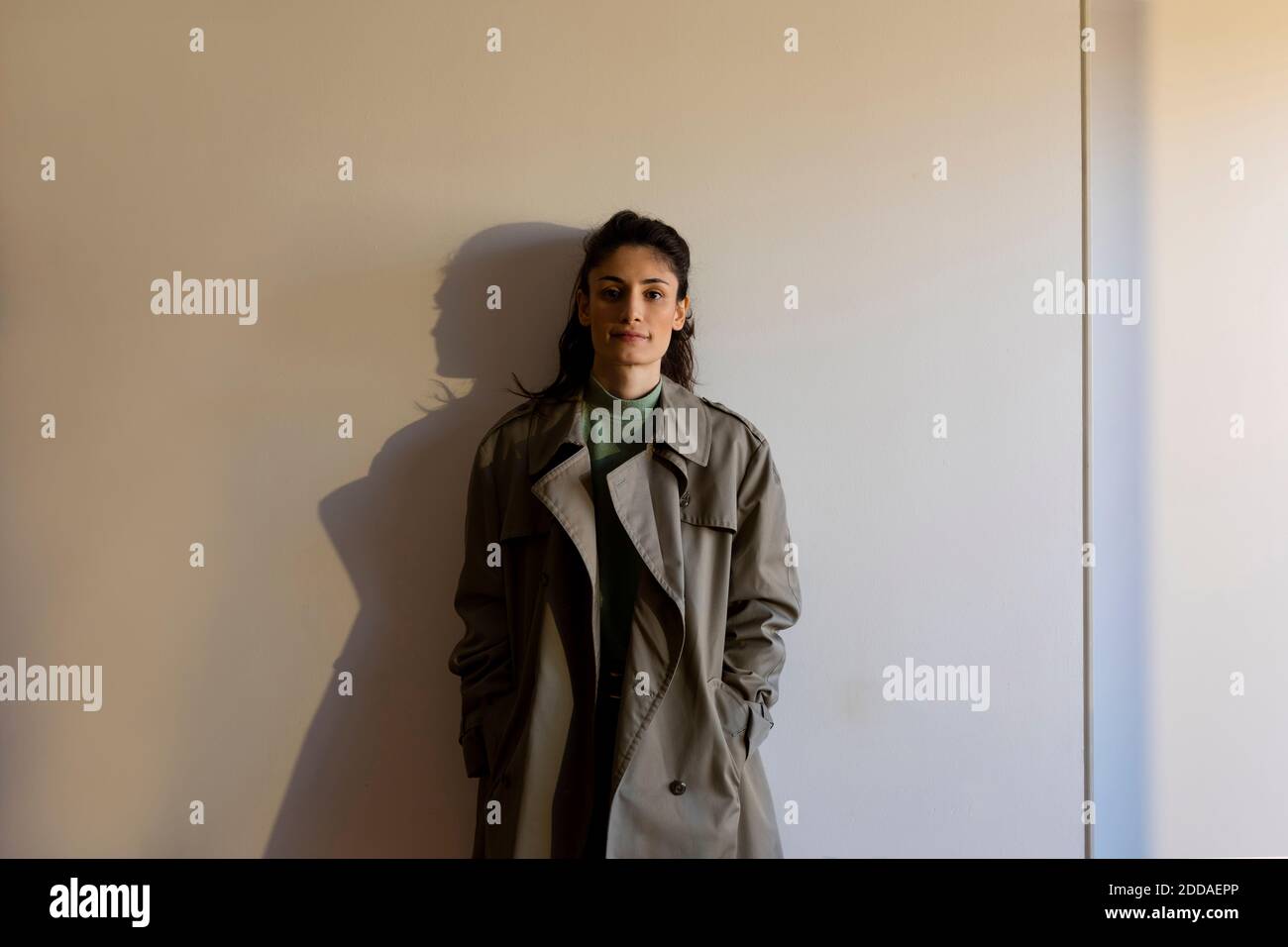 Weibliche Modell trägt Jacke mit Händen in den Taschen stehen gegen Wand Stockfoto Weibliche Modell trägt Jacke mit Händen in den Taschen stehen gegen Wand Stockfoto
