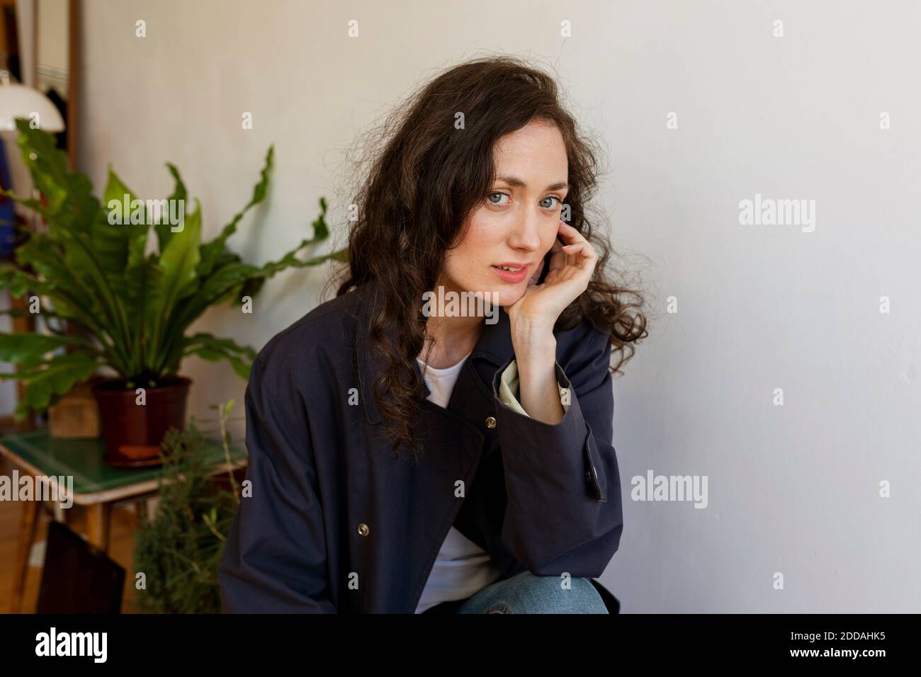 Schöne Frau mit der Hand am Kinn zu Hause sitzen Stockfoto Schöne Frau mit der Hand am Kinn zu Hause sitzen Stockfoto
