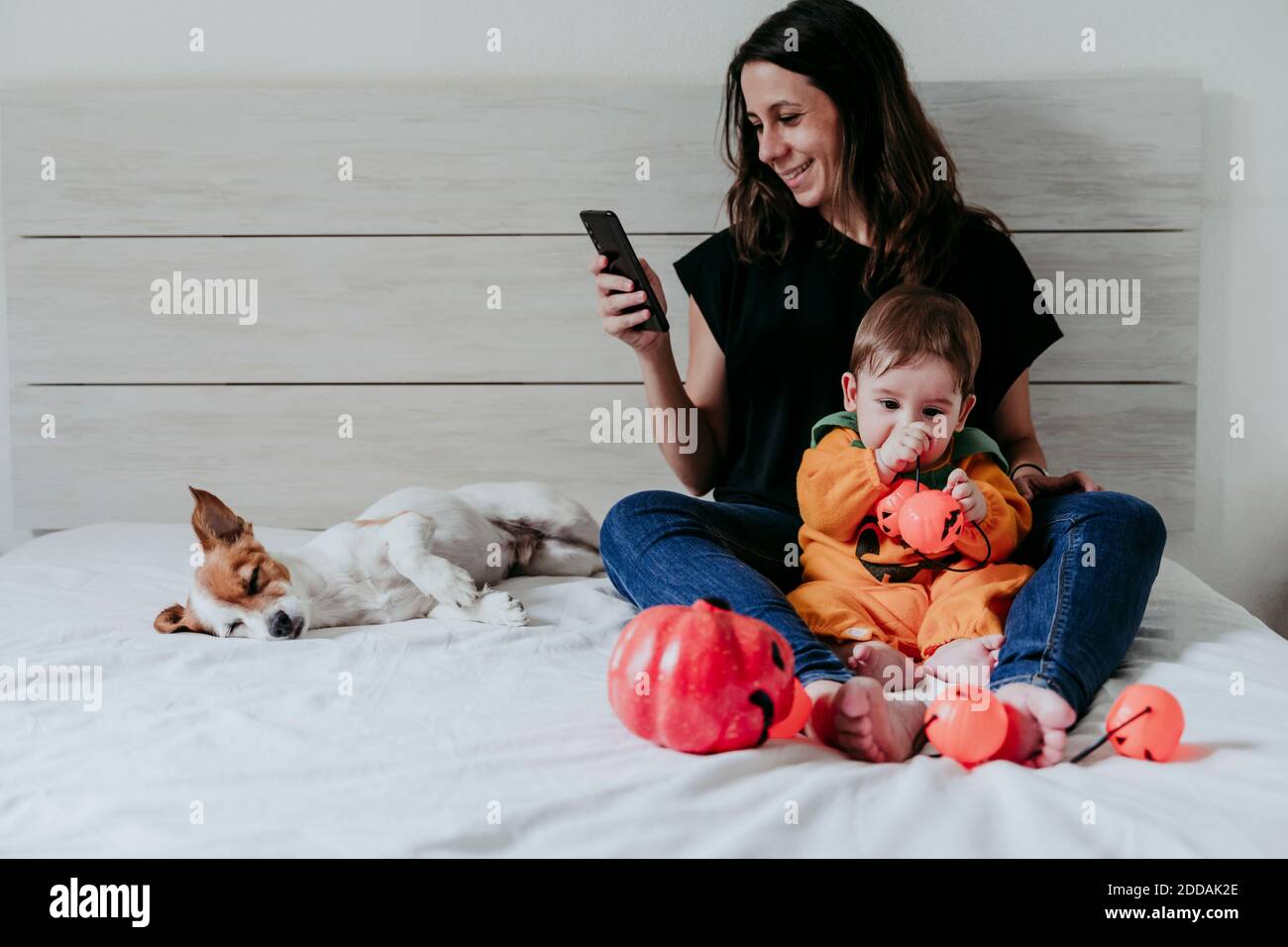 Mutter SMS auf Smartphone, während Sohn mit spielt Spielzeug sitzt zu Hause Stockfoto