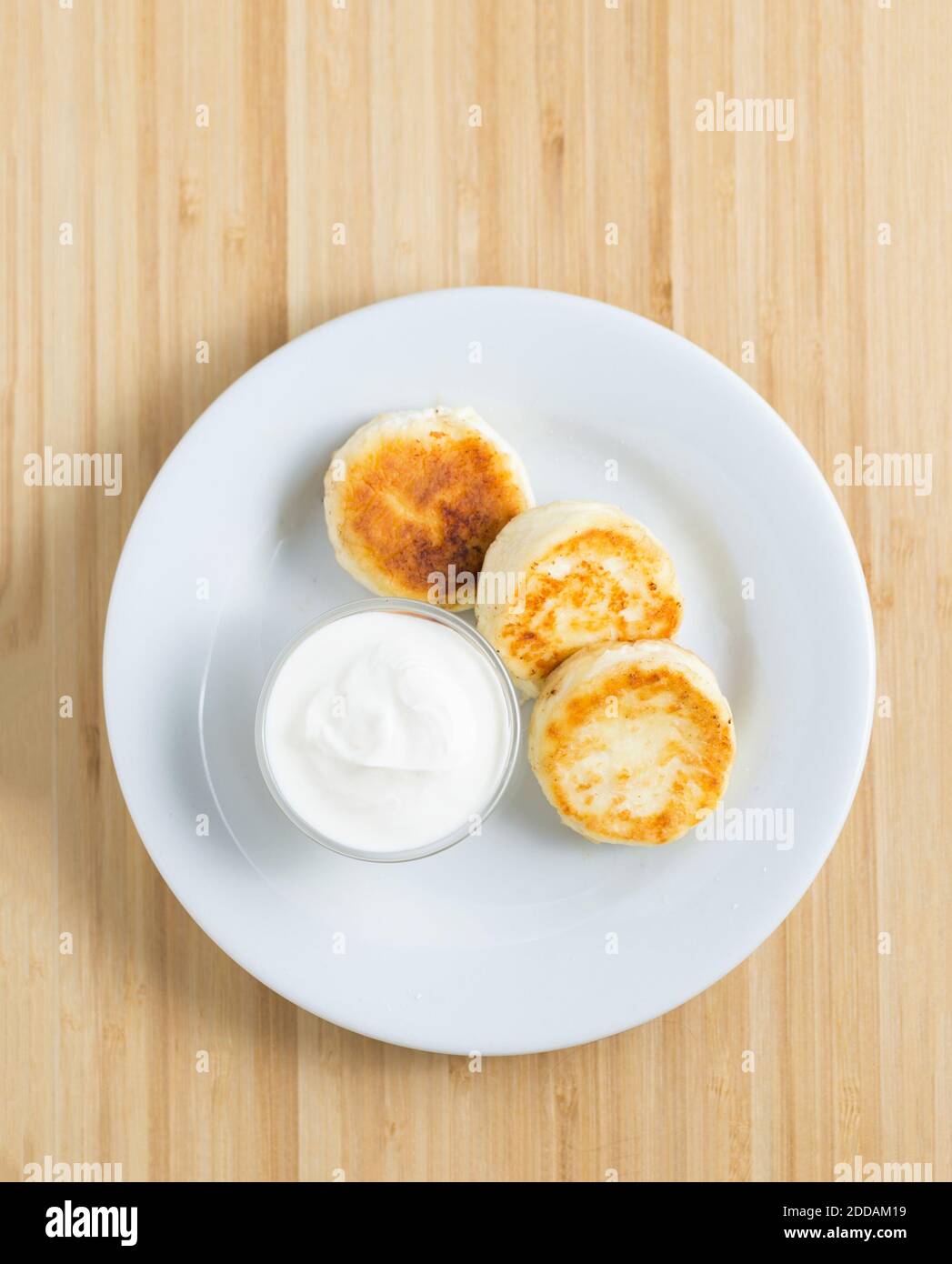 Hüttenkäse Pfannkuchen mit saurer Sahne auf dem Holzhintergrund Stockfoto