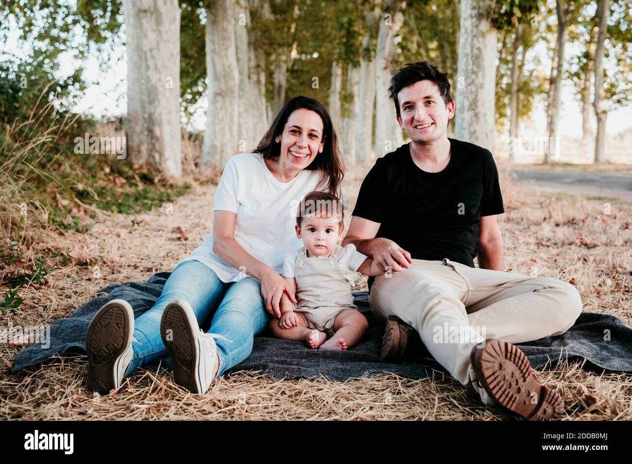 Lächelnder Mann und Frau, die mit dem Jungen auf der Decke sitzen Im Freien Stockfoto