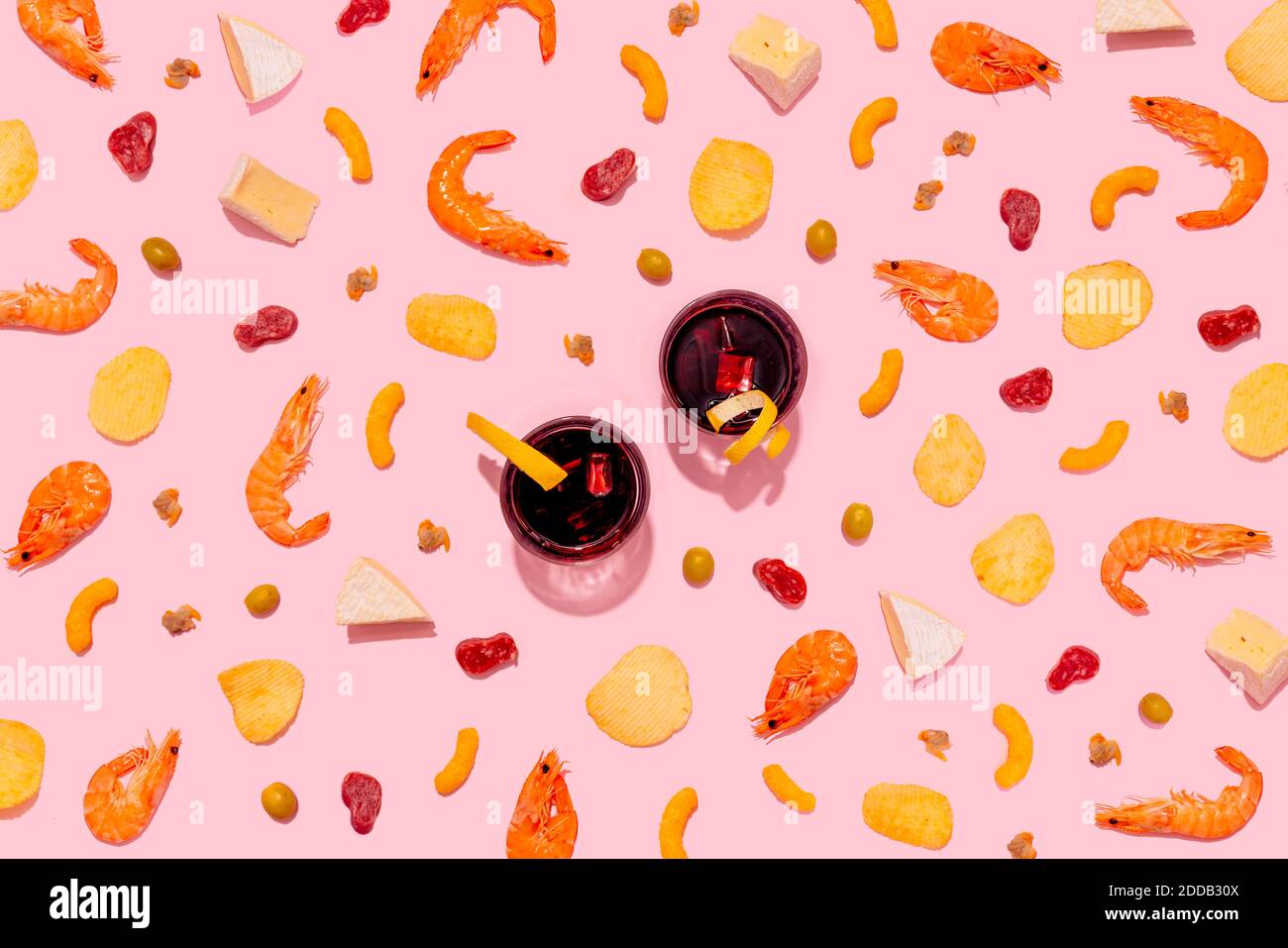 Wermut-Getränk mit Garnelen, Käse, Herzmuscheln, Brotstäbchen, Kartoffelchips, Käsepuffs, Oliven und Wurst auf rosa Hintergrund Stockfoto