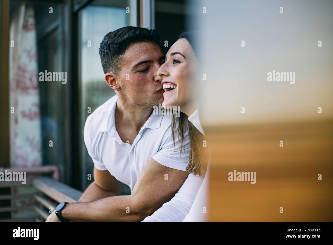 Freund küssen Frau, während lehnte an Balkon Geländer Stockfoto