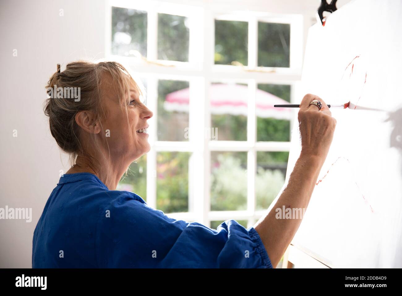 Ältere Frau Malerei Bild auf Leinwand zu Hause Stockfoto