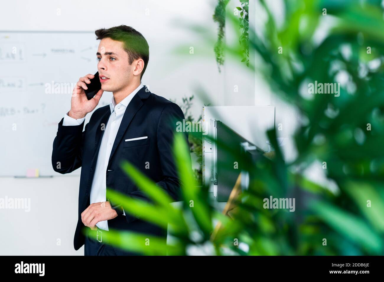 Gut aussehend junge Mann professionell sprechen am Telefon, während im Stehen Kreativer Arbeitsplatz Stockfoto