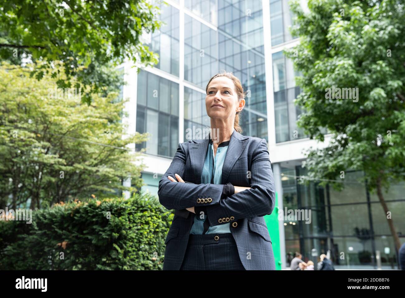 Geschäftsfrau mit gekreuzten Armen steht im Büropark Stockfoto