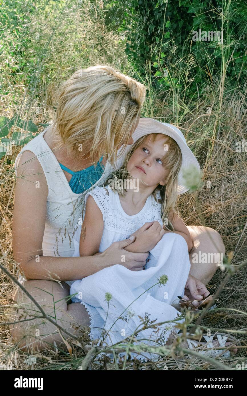 Mutter und Tochter schauten einander an, während sie darauf saßen Feld während des Urlaubs Stockfoto