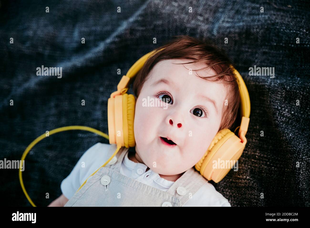 Niedlicher Baby Junge trägt Kopfhörer und macht Gesichtsausdruck beim  Liegen Auf Decke im Freien Stockfotografie - Alamy
