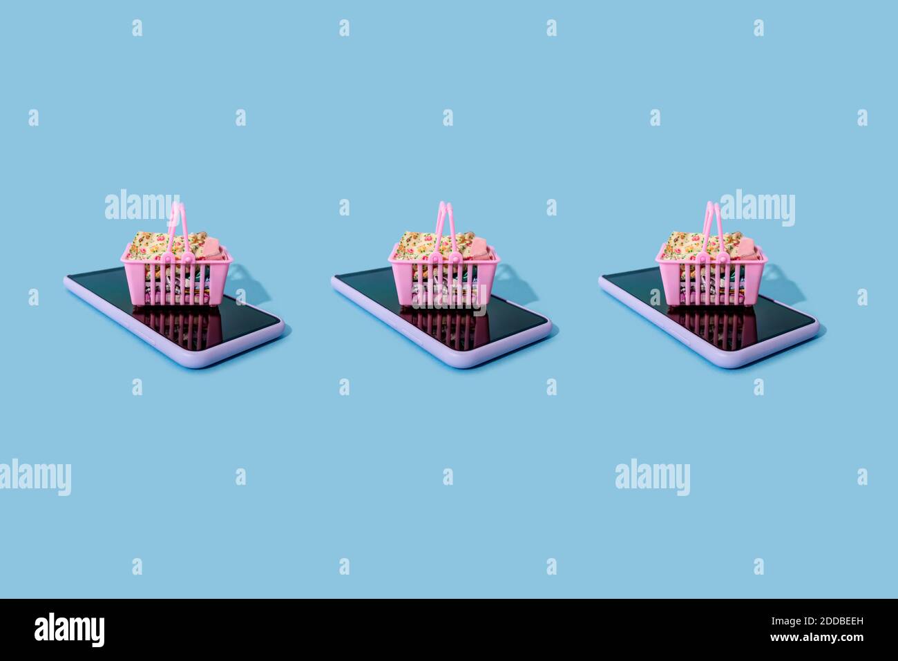 Reihe von Mini-Einkaufskörbe auf der Smart liegen Telefone Stockfoto