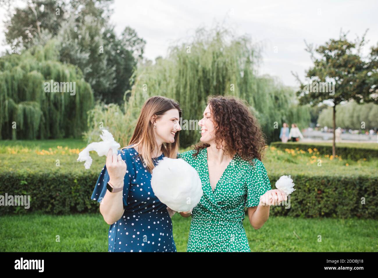 Lächelnde Freundinnen essen große Zuckerwatte im Park Stockfoto