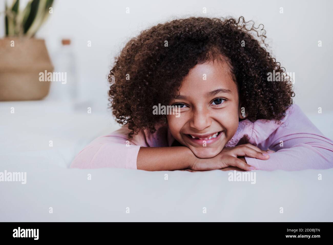 Lächelndes Mädchen liegt vorne im Schlafzimmer zu Hause Stockfoto