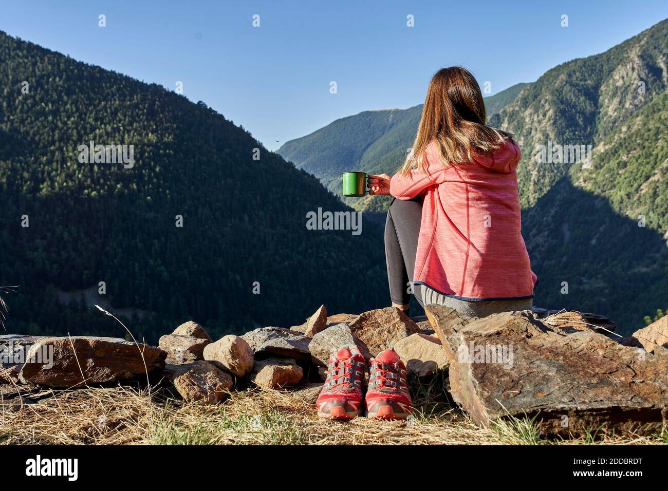 Frau mittleren Erwachsenen Blick auf die Ansicht während Kaffee trinken sitzen Auf Stein im Wald Stockfoto