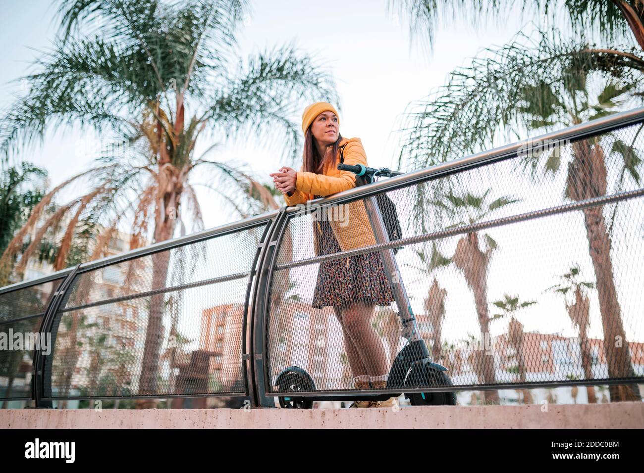Reife Frau mit Elektro-Push-Roller auf Geländer lehnt Stockfoto
