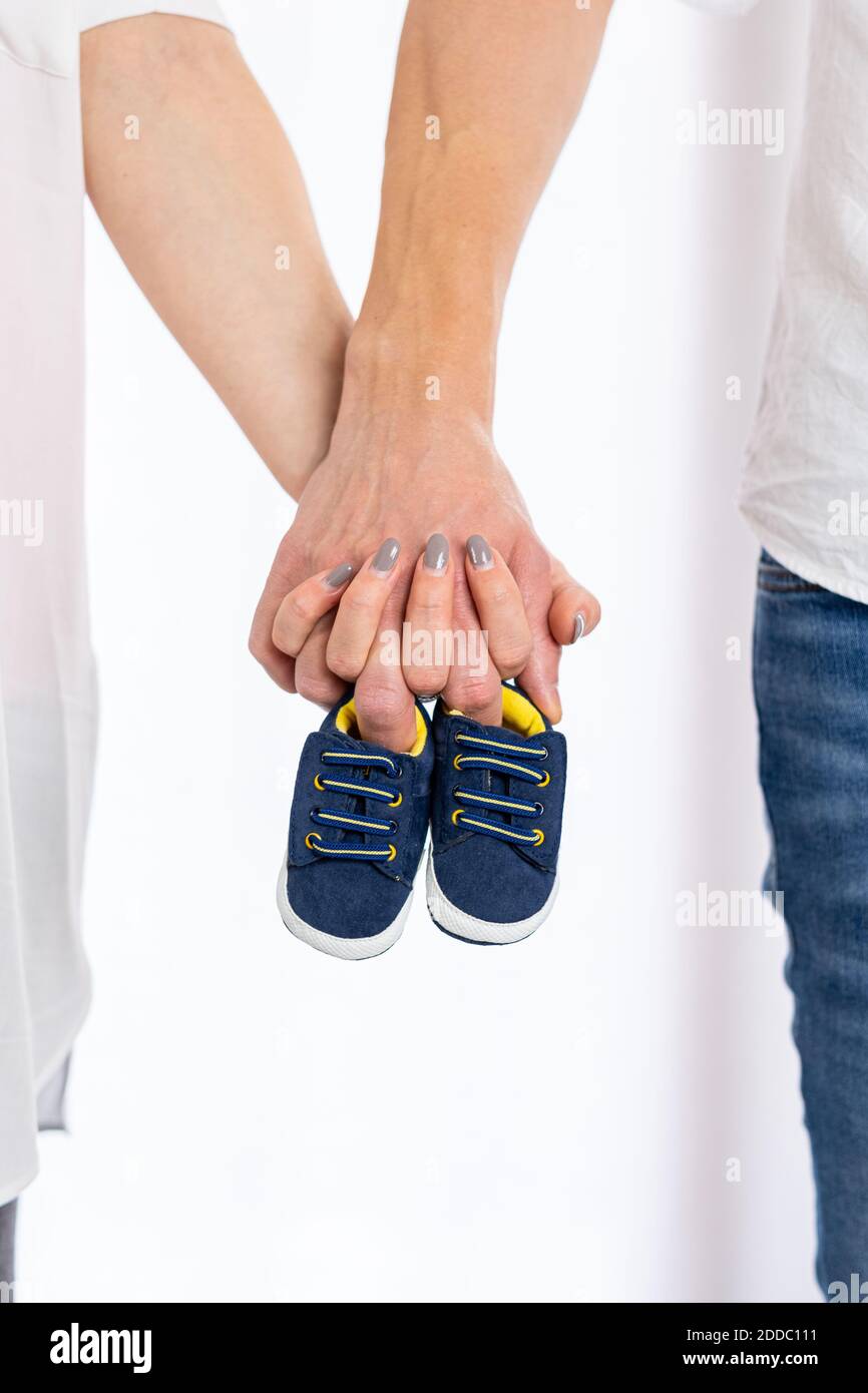 Nahaufnahme Bild von glücklichen Paar der schwangeren Mutter mit Vater hält Hände kleine Schuhe. Paar Hände halten Baby Jungen Schuhe Stockfoto