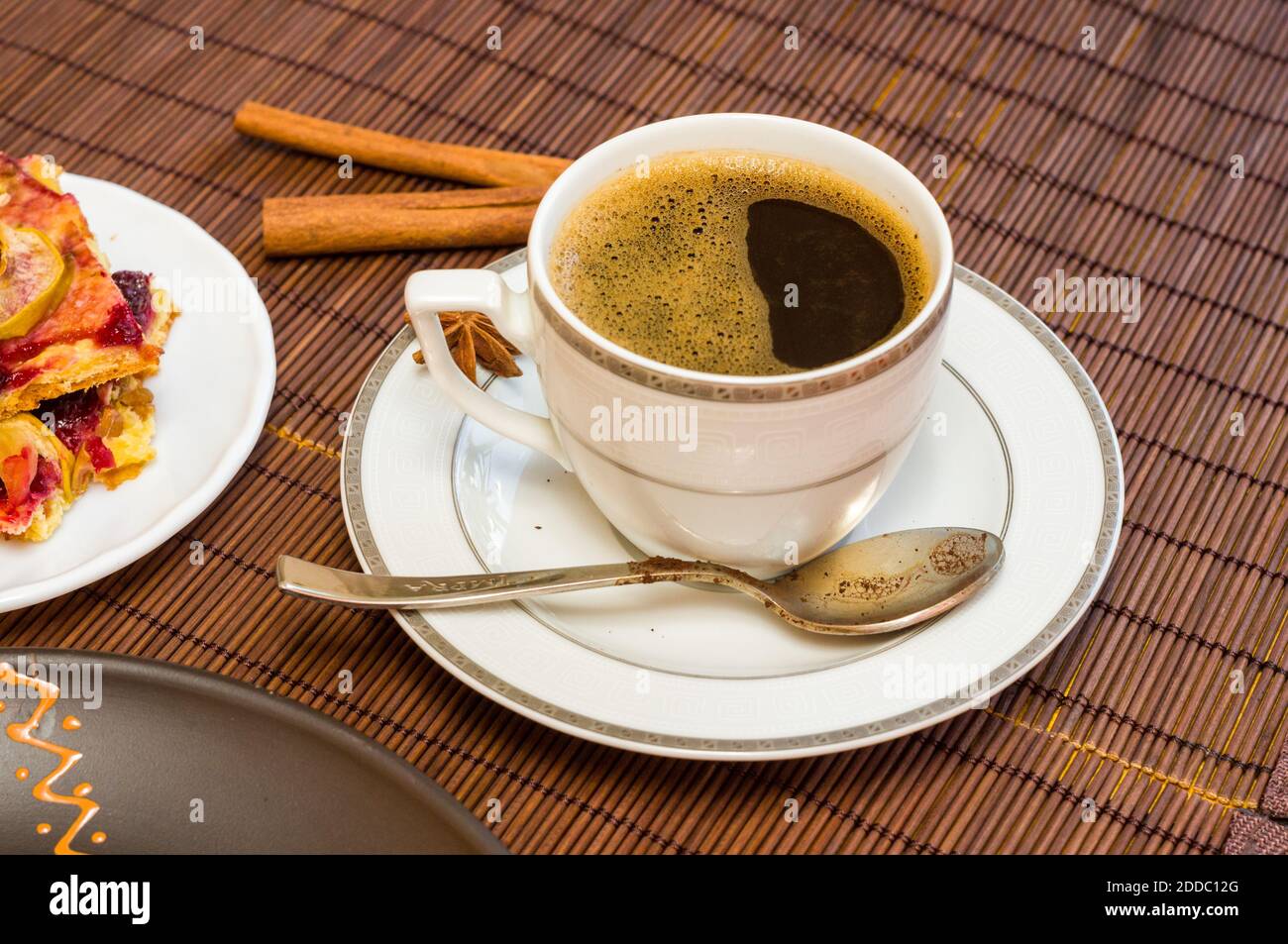 Stillleben - eine Tasse schwarzen Kaffee, hausgemachte Kekse mit Obst auf einer Bambusmatte Stockfoto