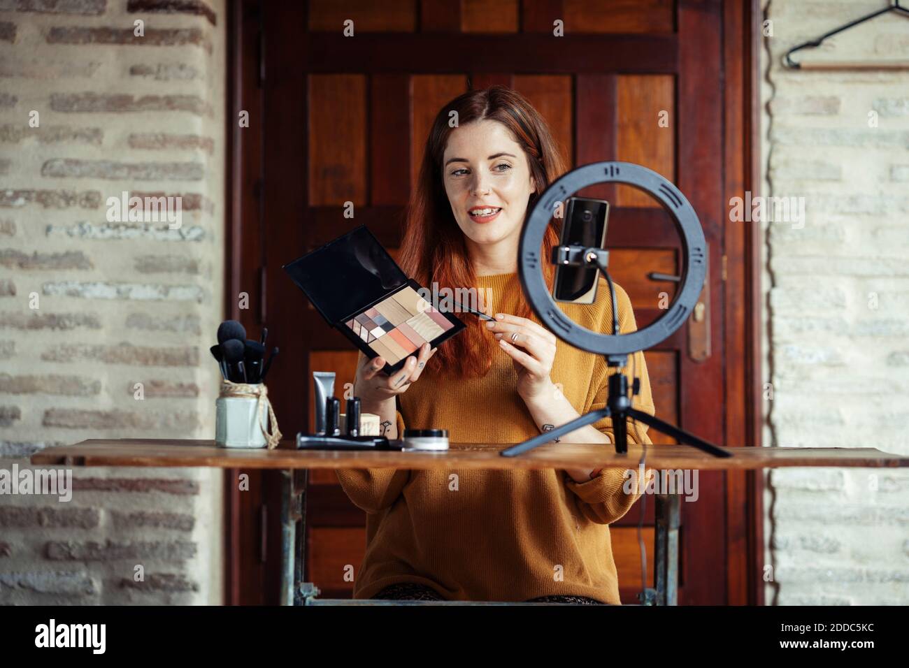 Kosmetikerin macht Make-up Tutorial auf Handy im Stehen Zu Hause Stockfoto