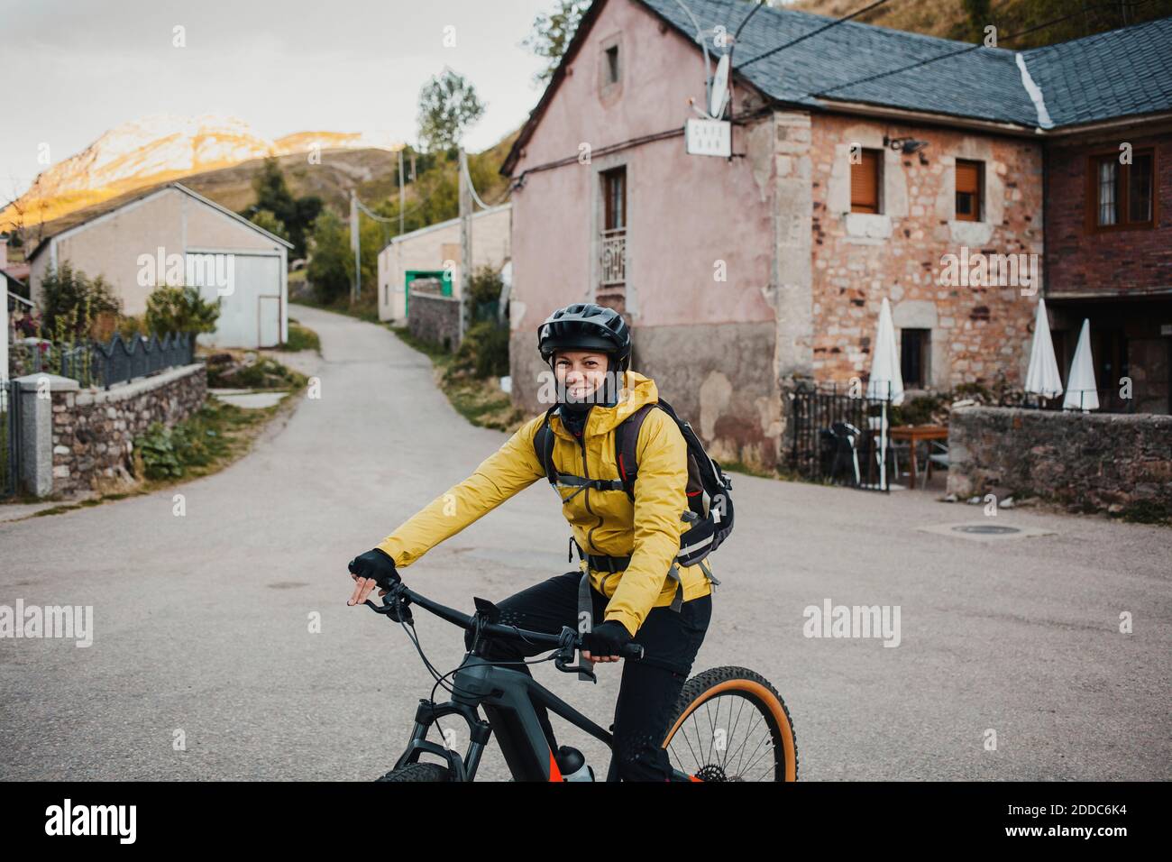 Mittlere Erwachsene Frau in warmer Kleidung Reiten Mountainbike auf der Straße während der Reise zum Somiedo Naturpark, Spanien Stockfoto