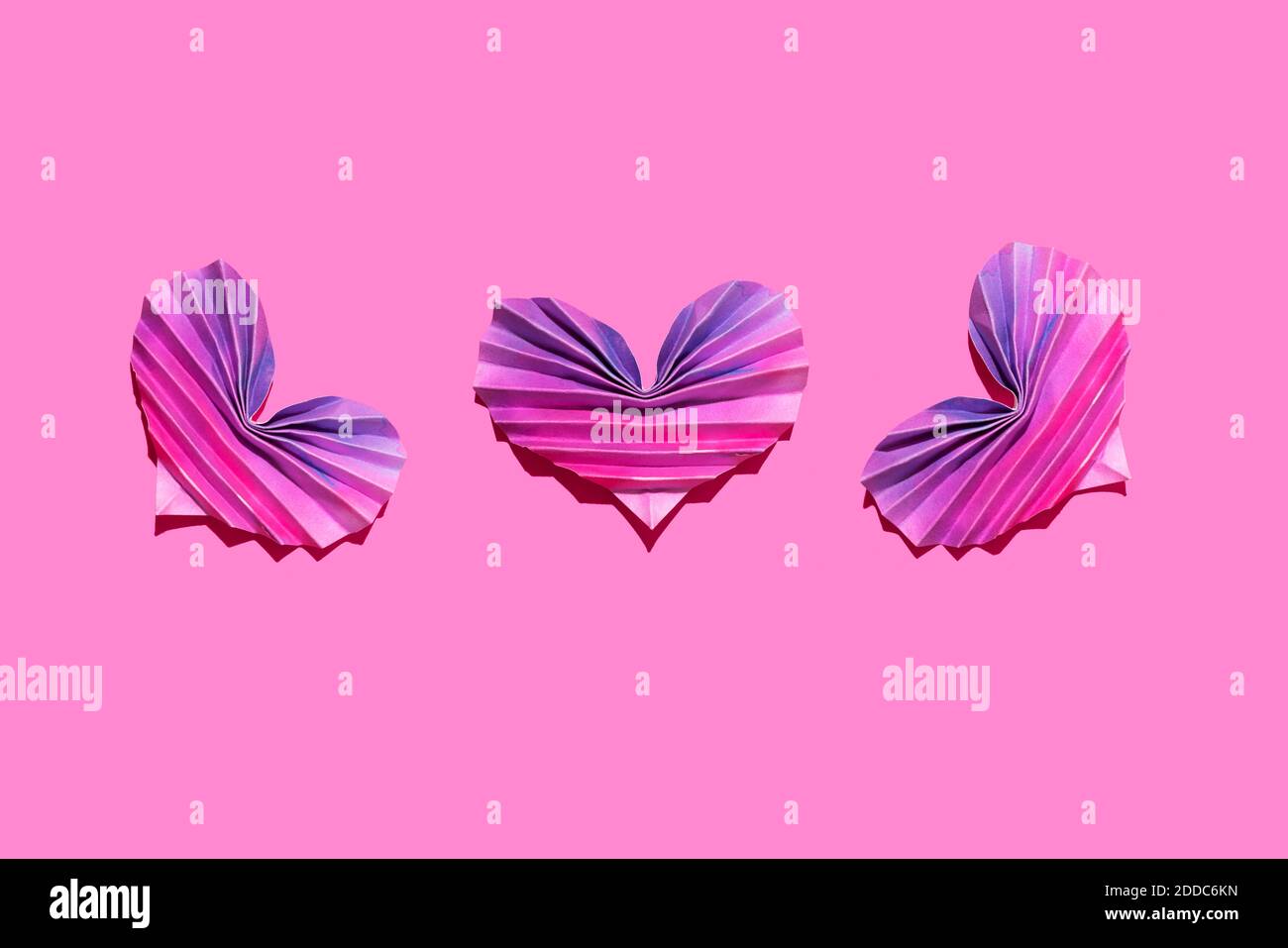 Studioaufnahme von drei rosa und lila Origami-Herzen Stockfoto