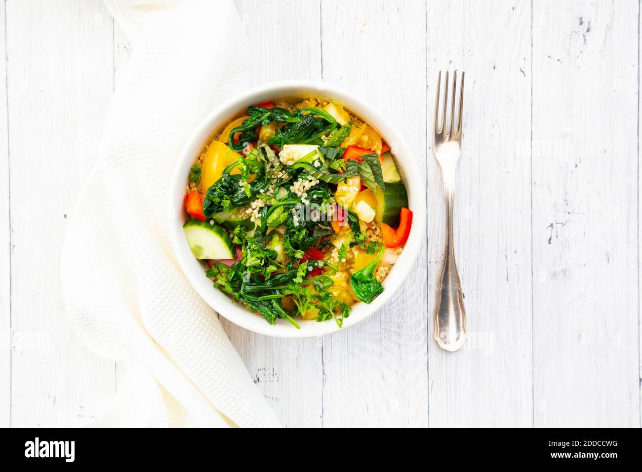 Schüssel warmer veganer Quinoa-Salat mit Spinat, Paprika, Gurken, Tomaten, Petersilie und Minze Stockfoto