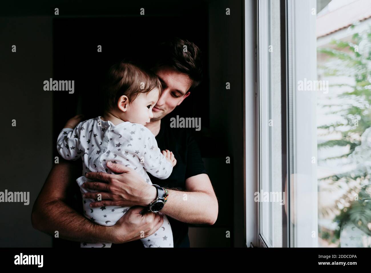 Vater hält Sohn beim Blick durch das Fenster zu Hause Stockfoto