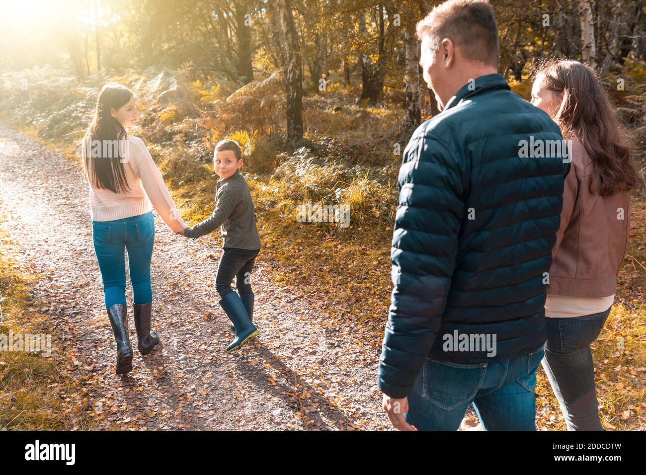 Geschwister blicken über die Schulter auf Eltern, die im Park zurücklaufen Im Herbst Stockfoto