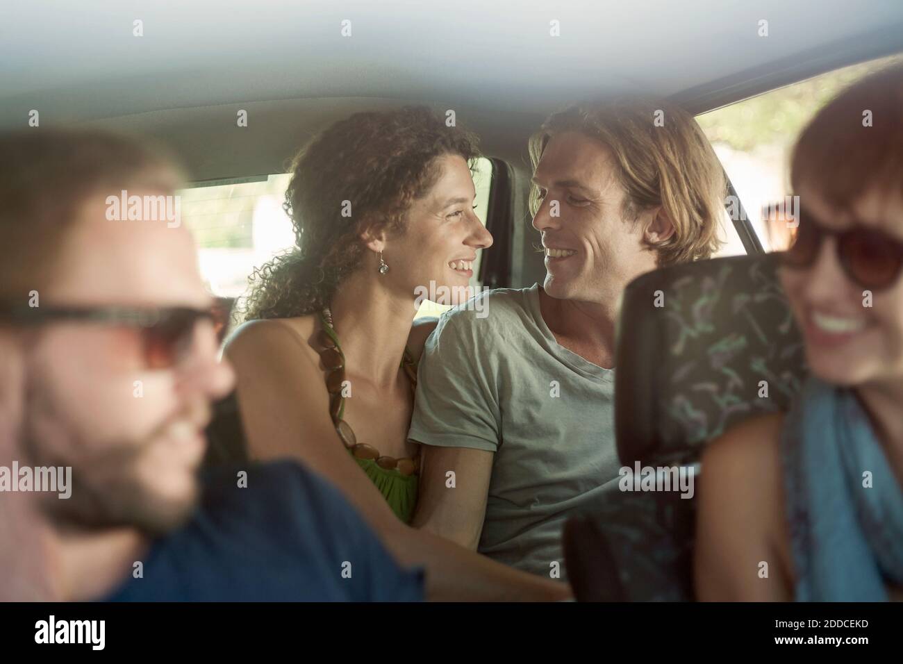 Lächelndes Paar mit Freunden, die während der Fahrt im Auto sitzen Stockfoto