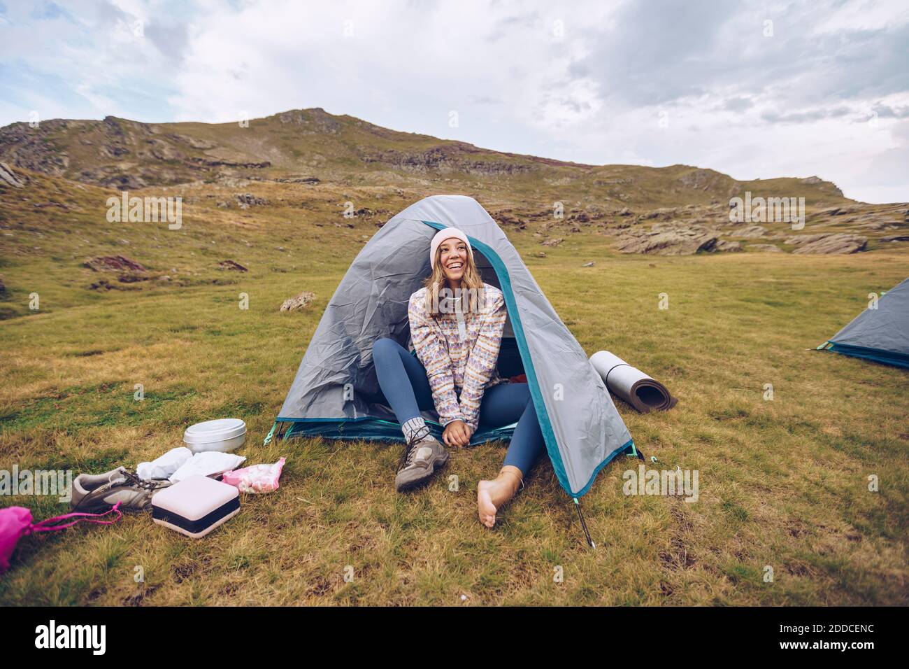 Junge Frau, die im Zelt auf dem Berg um Ibones von sitzt Anayet Stockfoto