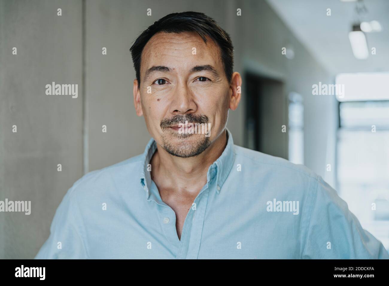 Ein hübscher Geschäftsmann, der auf dem Flur steht Stockfoto