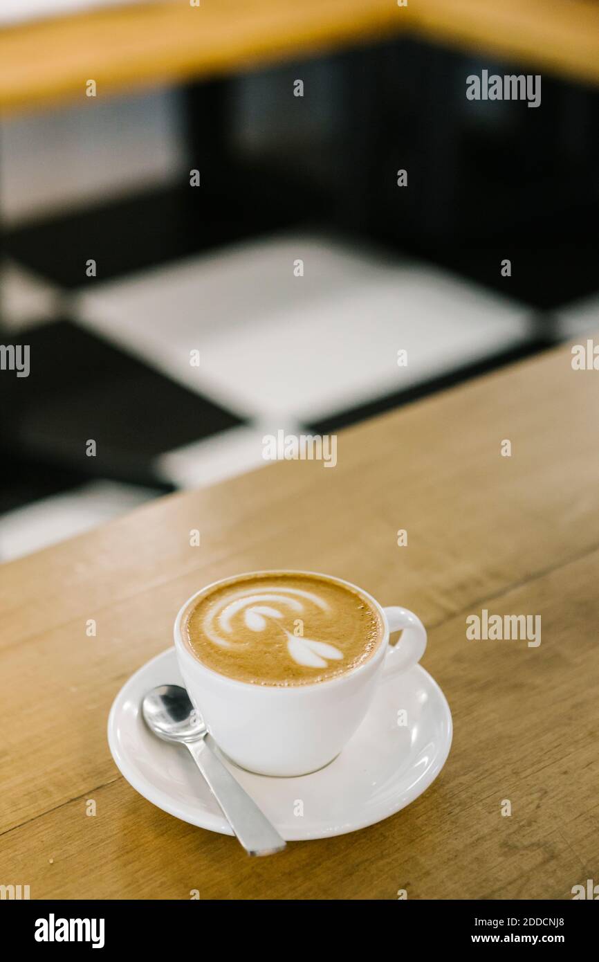 Cappuccino-Tasse mit Löffel auf dem Tisch im Café Stockfoto