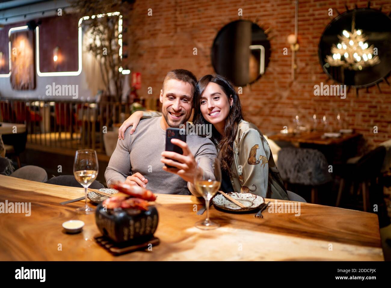 Lächelnde Freunde, die Selfie machen, während sie am Tisch im Restaurant sitzen Stockfoto