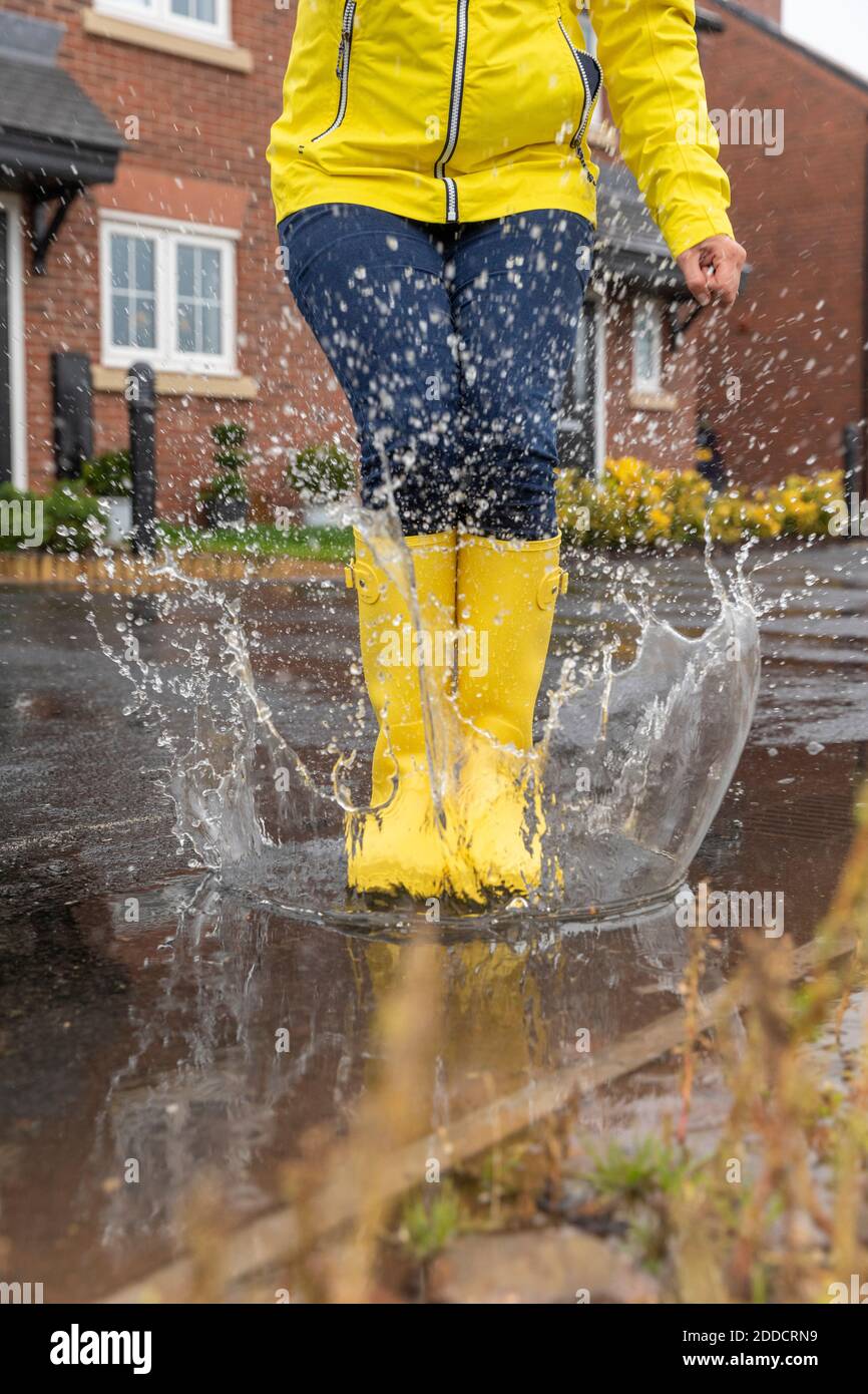 Frau springt in der Wasserpfütze während der Regenzeit Stockfoto