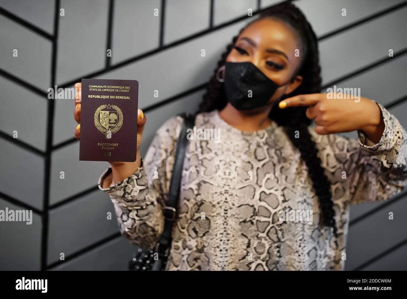 Afrikanische Frau trägt schwarze Gesichtsmaske zeigen Senegal Pass in der Hand. Coronavirus in Afrika Land, Grenze Schließung und Quarantäne, Virus Ausbruch Konz Stockfoto