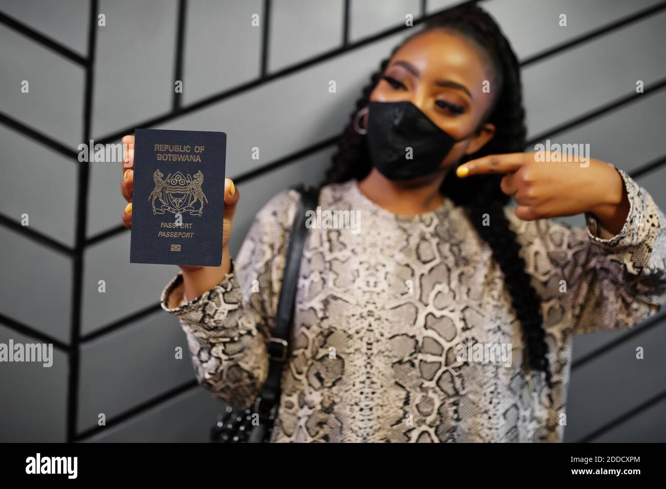 Afrikanische Frau trägt schwarze Gesichtsmaske zeigen Botswana Pass in der Hand. Coronavirus in Afrika Land, Grenze Schließung und Quarantäne, Virus Ausbruch con Stockfoto