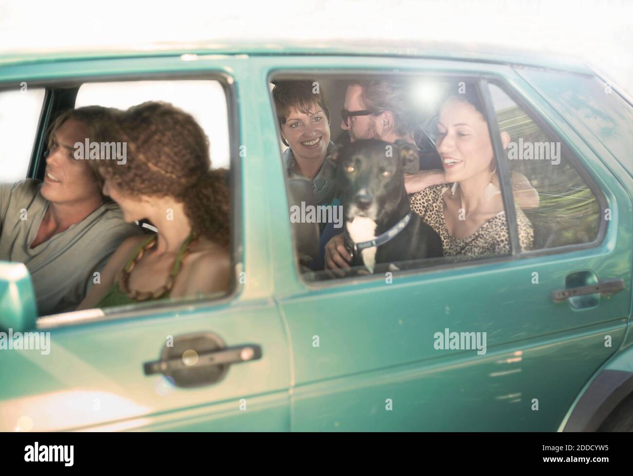 Lächelnde männliche und weibliche Freunde sitzen im Auto während der Straße Reise Stockfoto