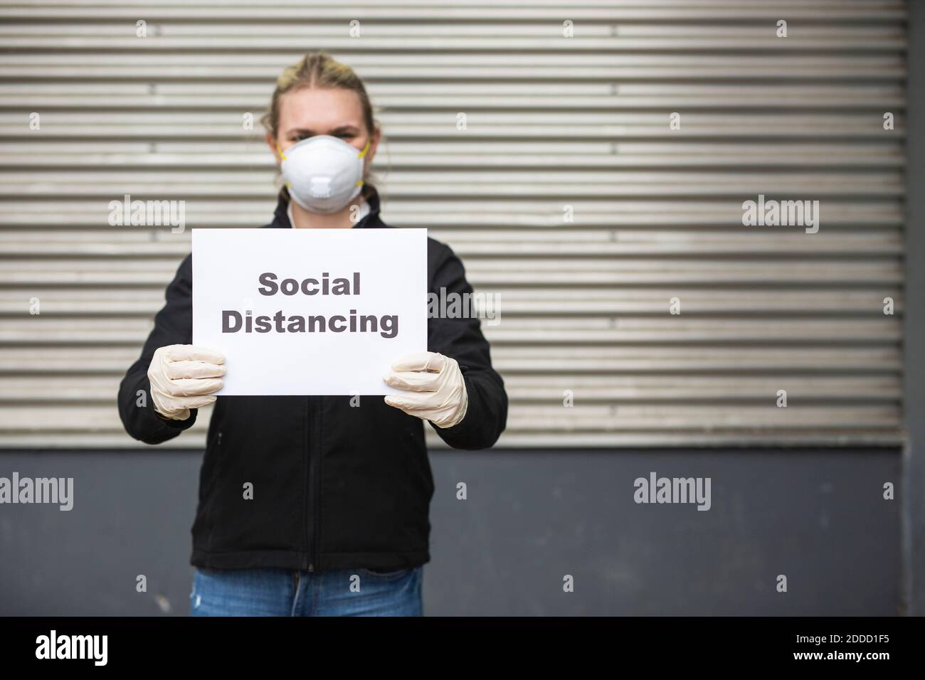 Teenager-Mädchen tragen Schutzmaske und Handschuhe halten Zeichen mit Anforderung „soziale Distanzierung“ Stockfoto