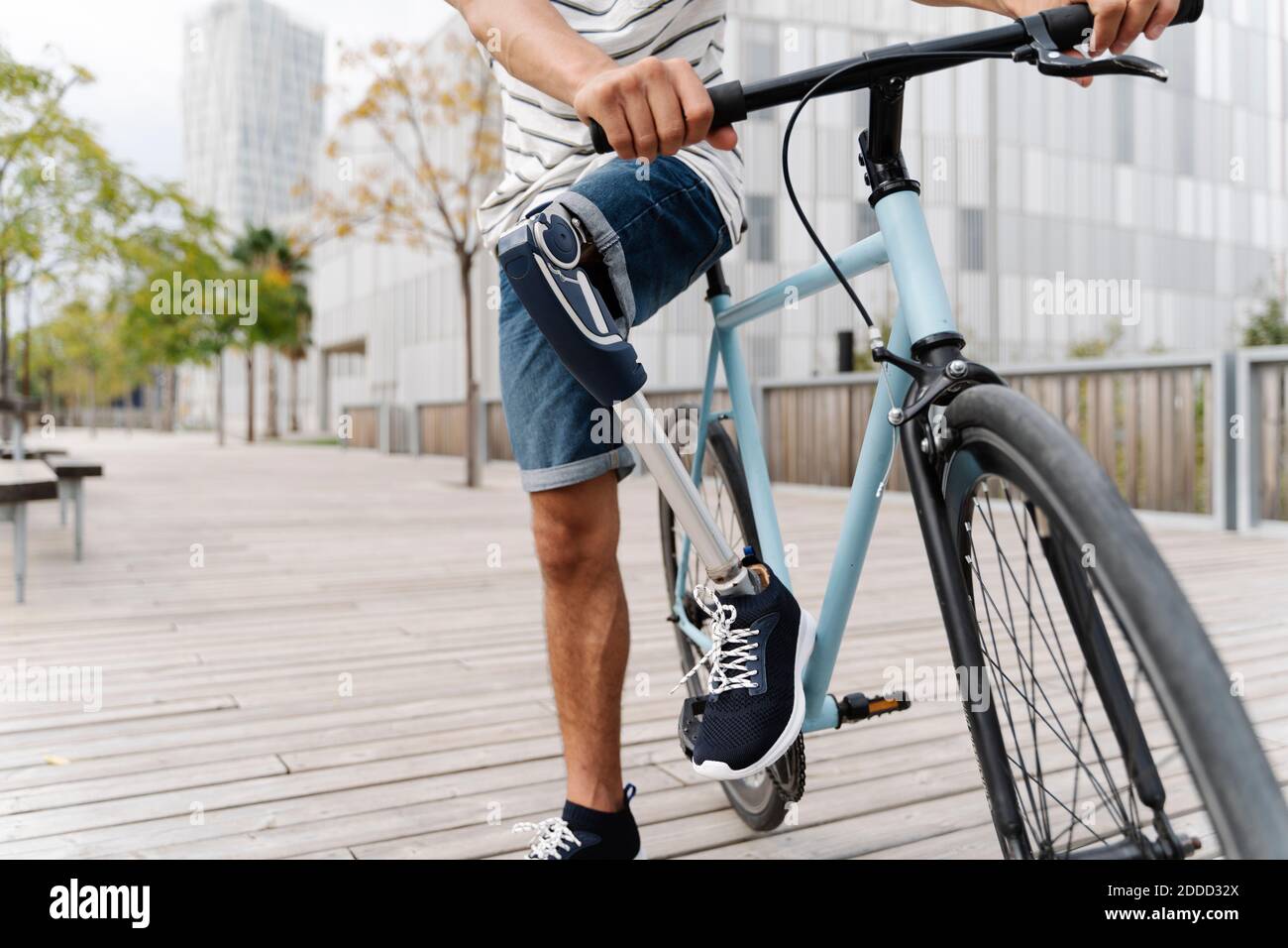 Niedriger Abschnitt des Menschen mit künstlichen Gliedmaßen Fahrrad fahren in Stadt Stockfoto