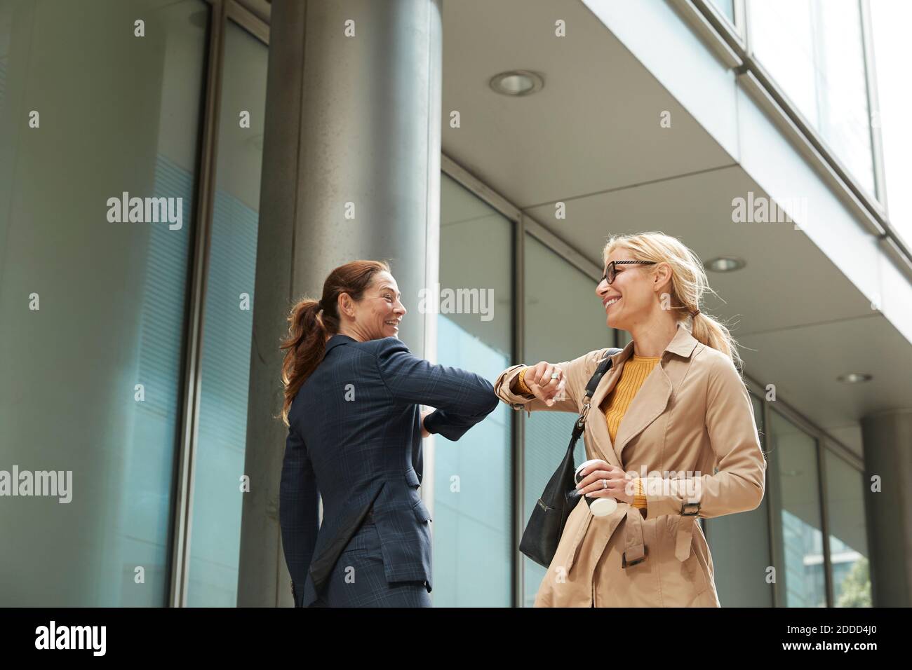 Geschäftsfrau und Kollege begrüßen mit Ellenbogenstoß, während sie im Stehen Stadt Stockfoto