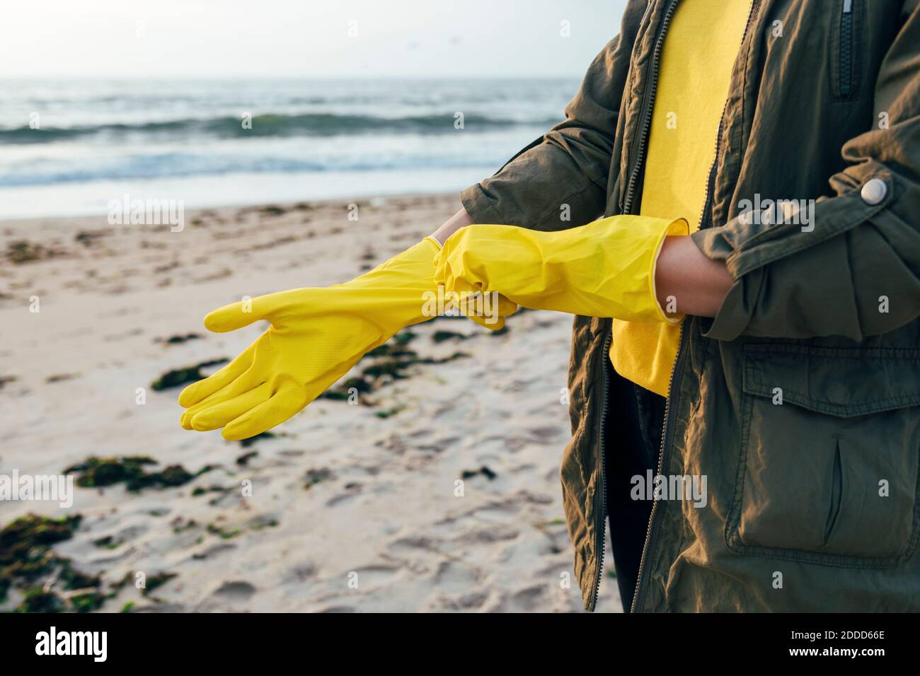 Mittlere Erwachsene Frau stehend und trägt Schutzhandschuh für die Reinigung Strand Stockfoto