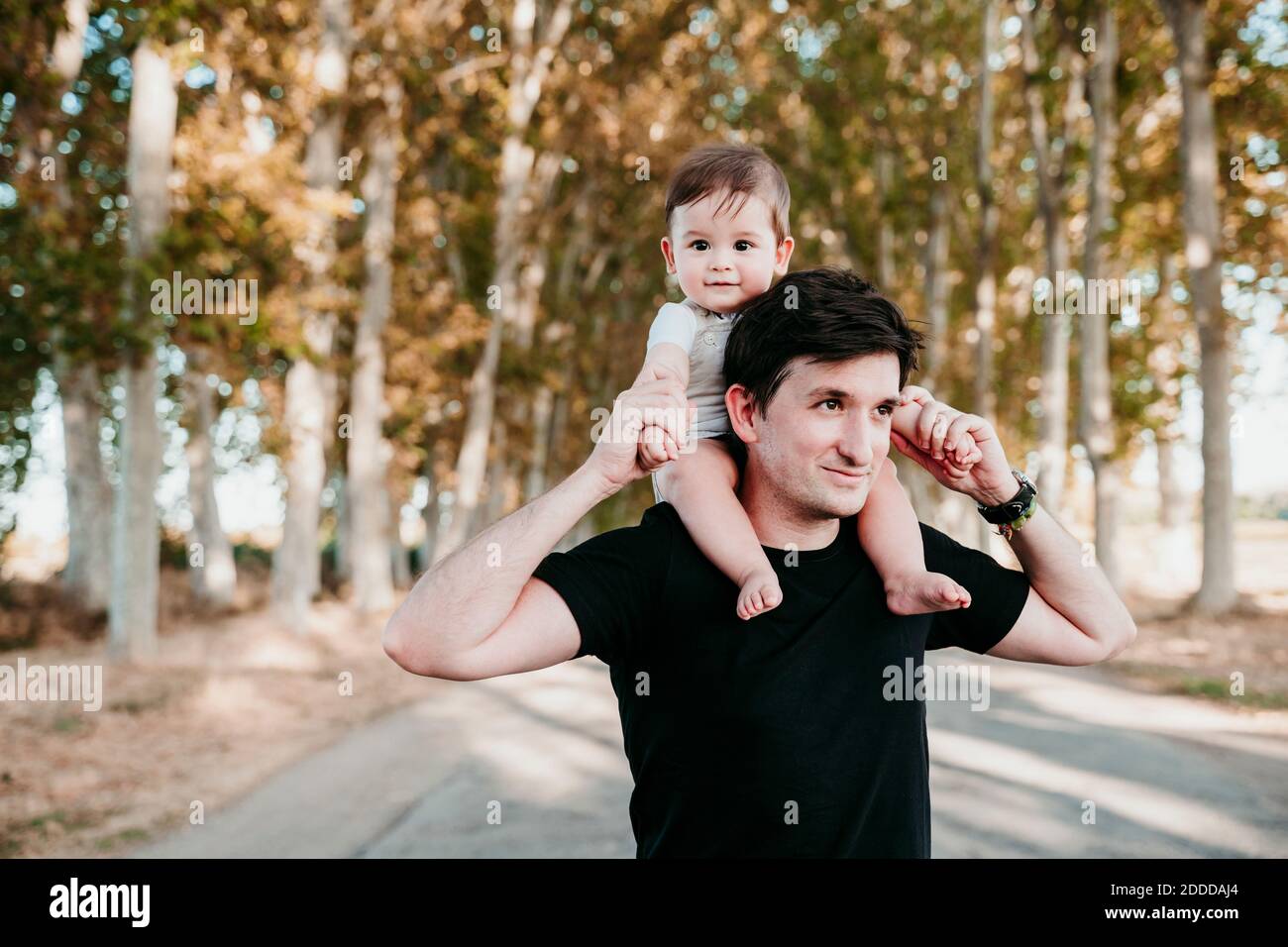 Lächelnder Vater trägt Baby Junge auf der Schulter, während im Freien stehen Stockfoto