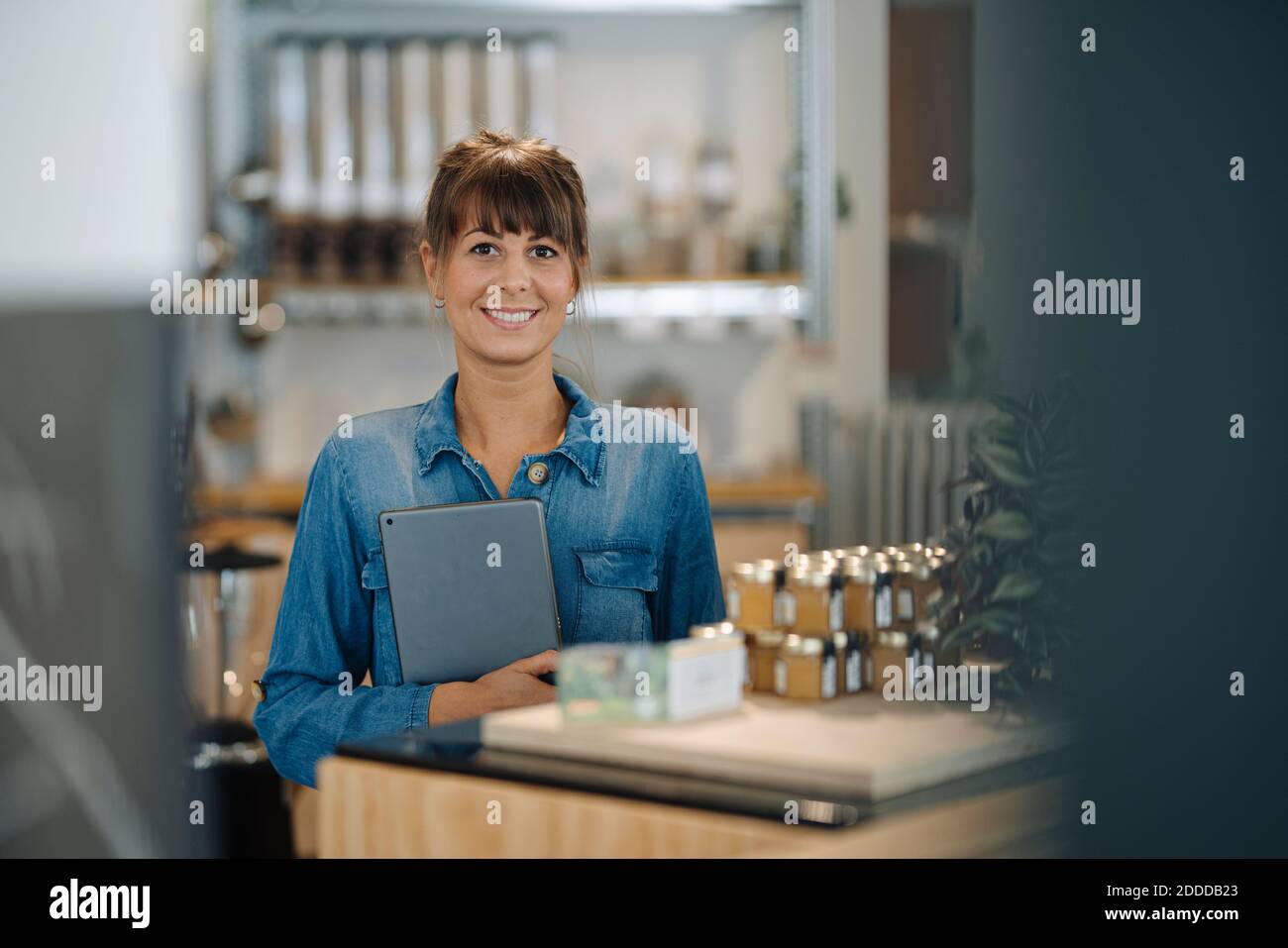 Glückliche weibliche Besitzerin hält digitale Tablette im Café stehen Stockfoto