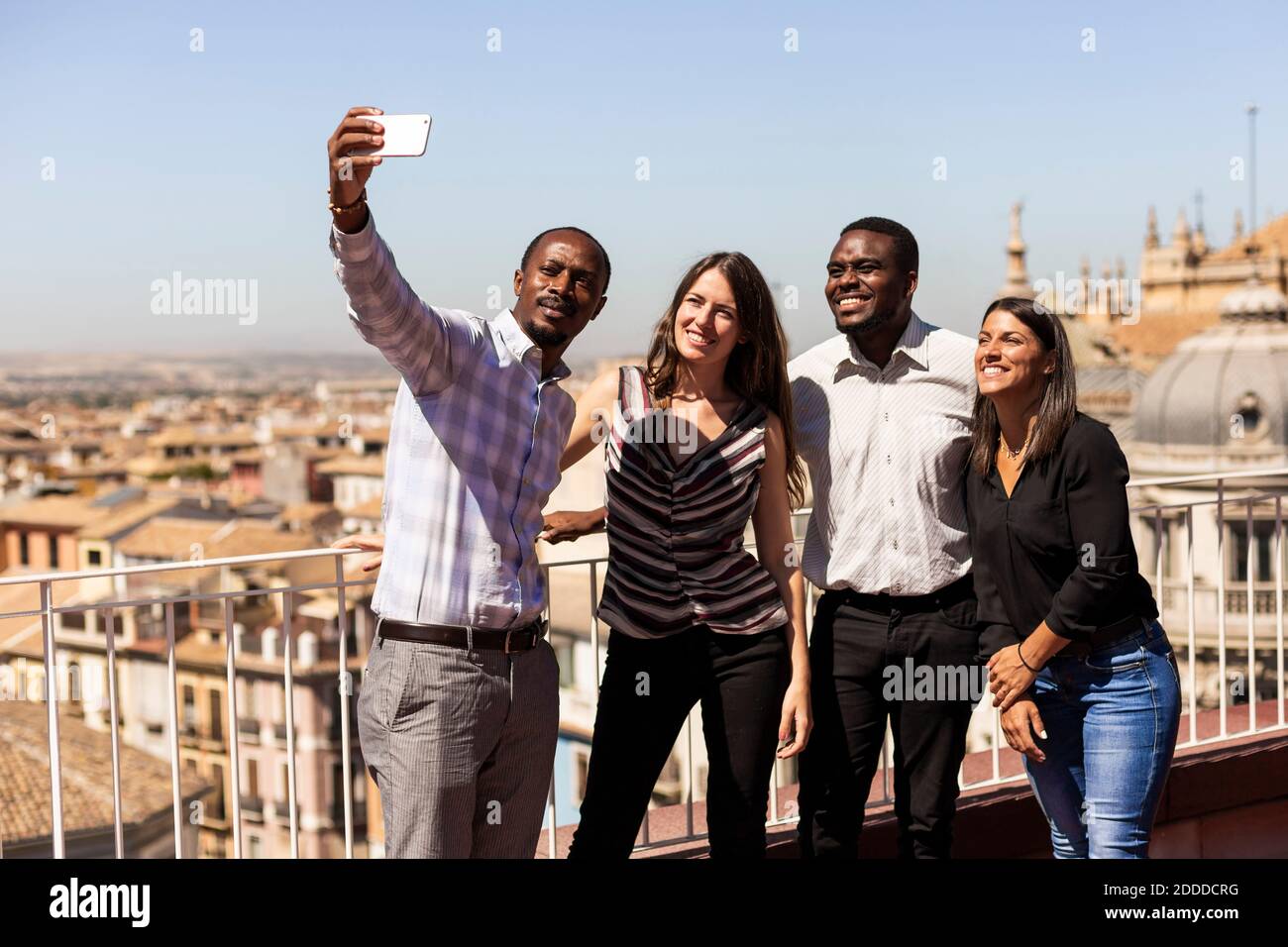 Glückliche, multiethnische Kollegen, die während der Pause Selfie auf dem Bürodach machen Stockfoto