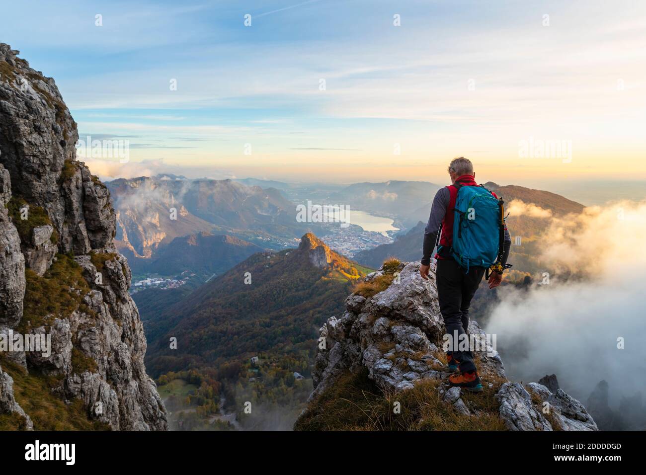 Nachdenklicher männlicher Wanderer, der während des Sonnenaufgangs auf Bergamasque Alps, Italien, auf dem Berggipfel läuft Stockfoto