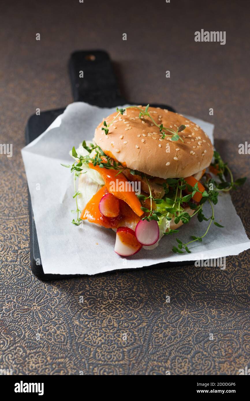 Veganer Burger mit Soja-Schnitzelstreifen, Paprika, Radieschen, Oregano und Salat Stockfoto