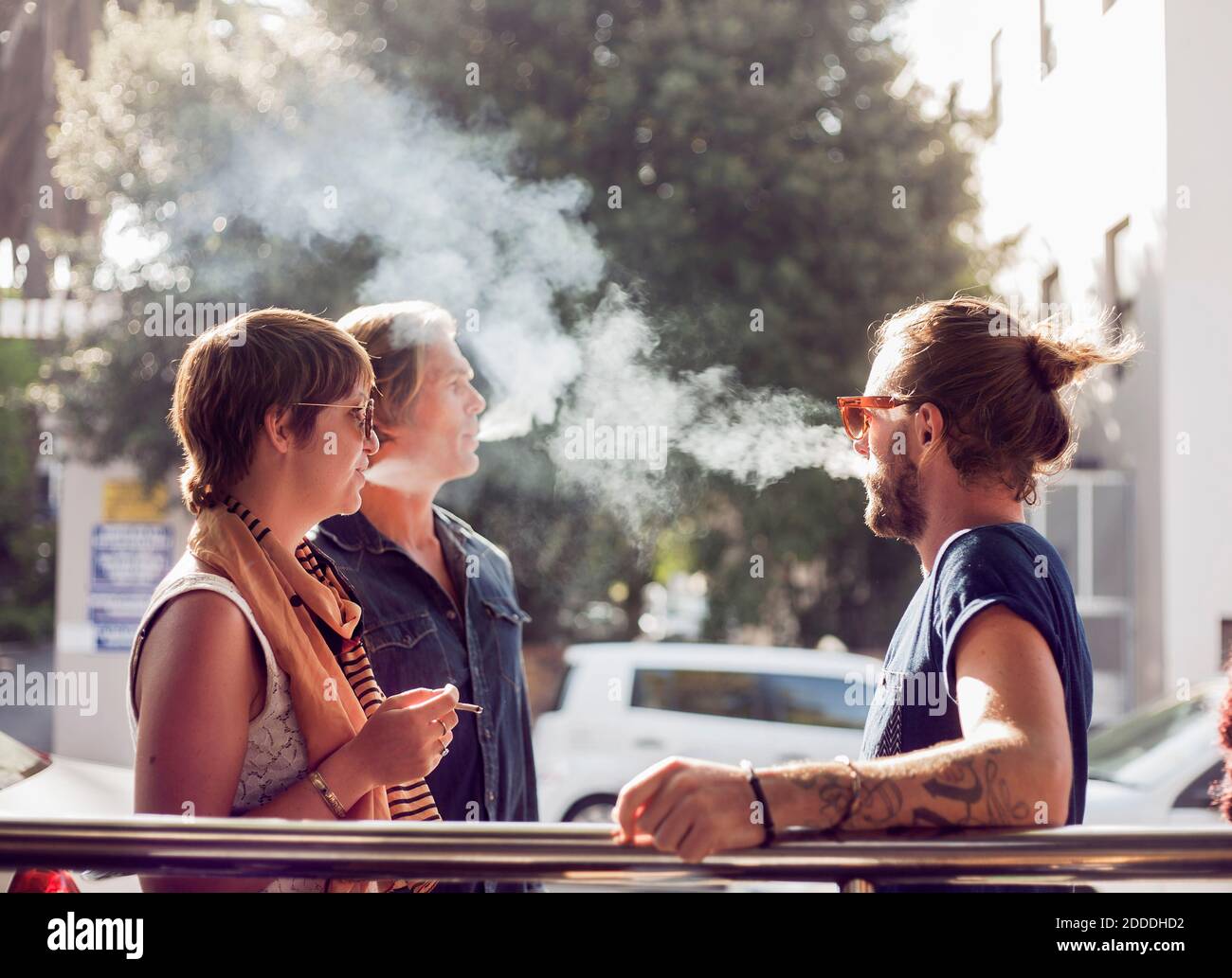Freunde rauchen, während sie draußen an sonnigen Tagen stehen Stockfoto