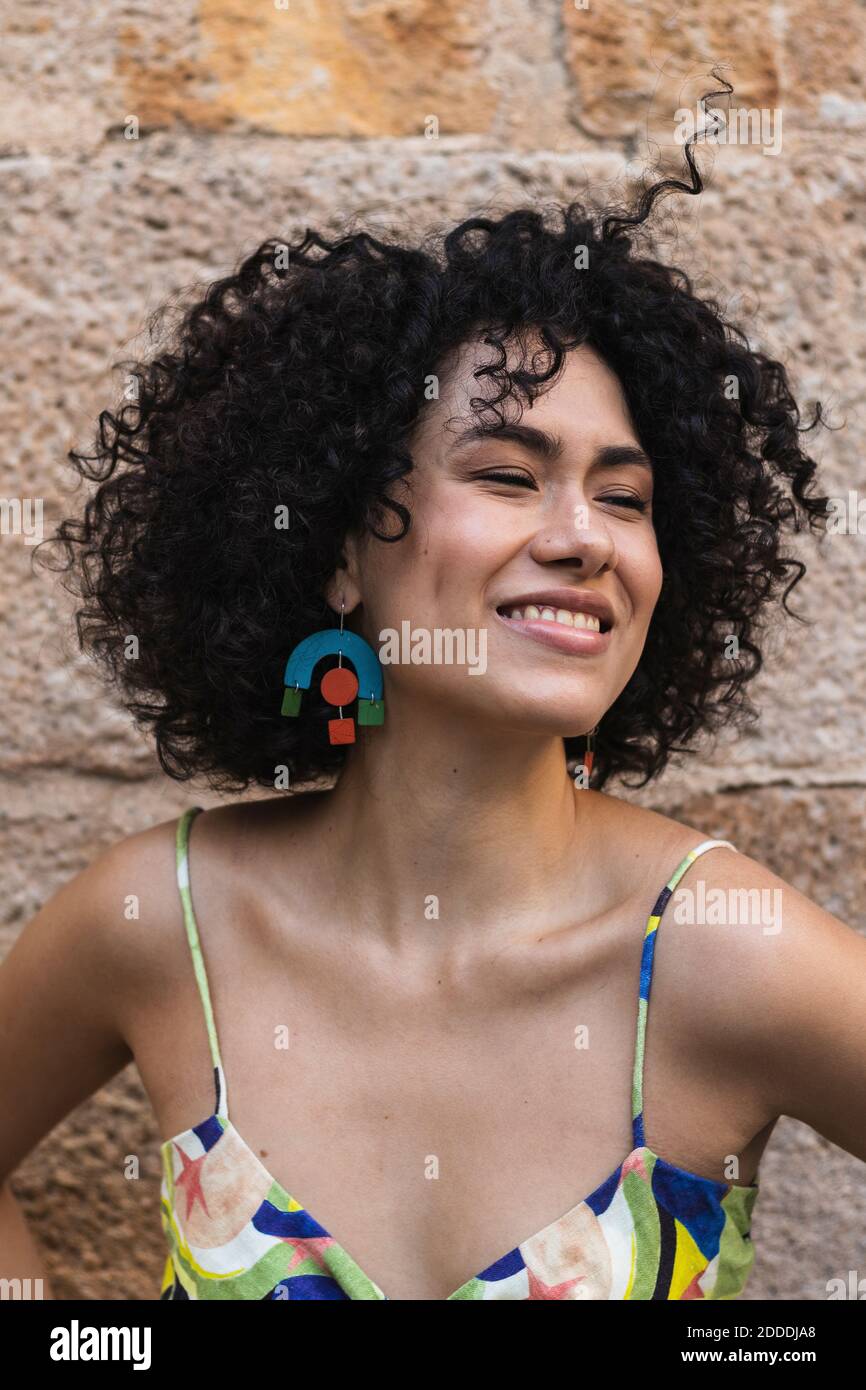 Attraktive junge Frau, die wegschaut, während sie sich an die Steinwand lehnt Stockfoto