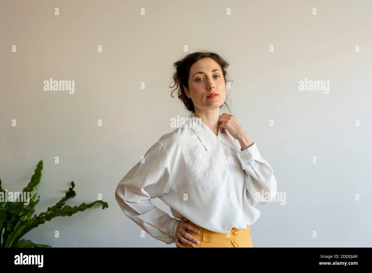 Schöne weibliche Modell mit Hand auf Hüfte tragen Retro-Stil Kleidung, die an der Wand steht Stockfoto Schöne weibliche Modell mit Hand auf Hüfte tragen Retro-Stil Kleidung, die an der Wand steht Stockfoto