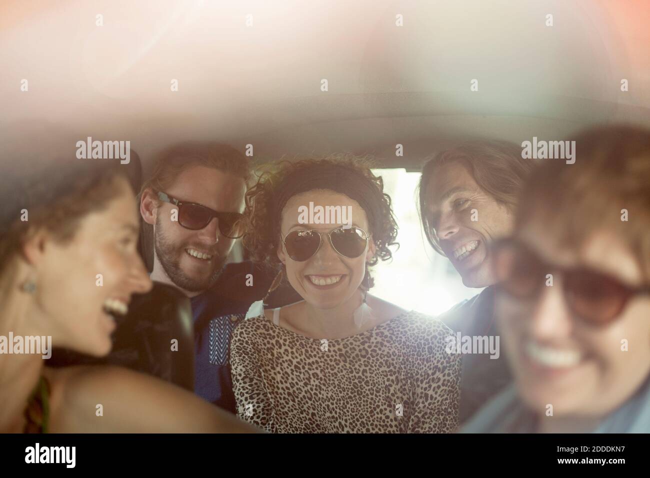 Lächelnde männliche und weibliche Freunde sitzen im Auto während der Straße Reise Stockfoto