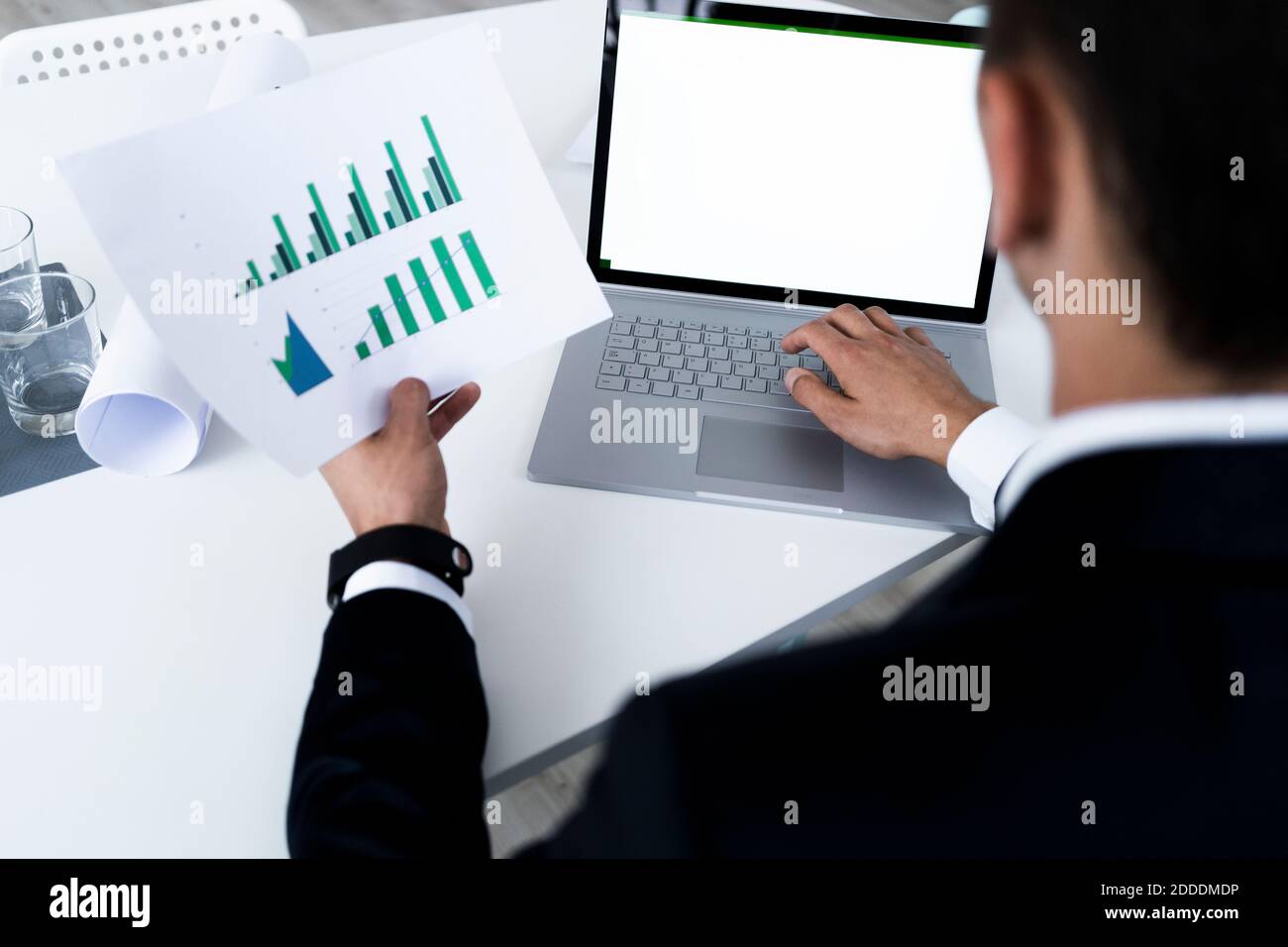 Junger Geschäftsmann analysiert Wachstumsdiagramm durch Laptop während der Planung an Kreativer Arbeitsplatz Stockfoto