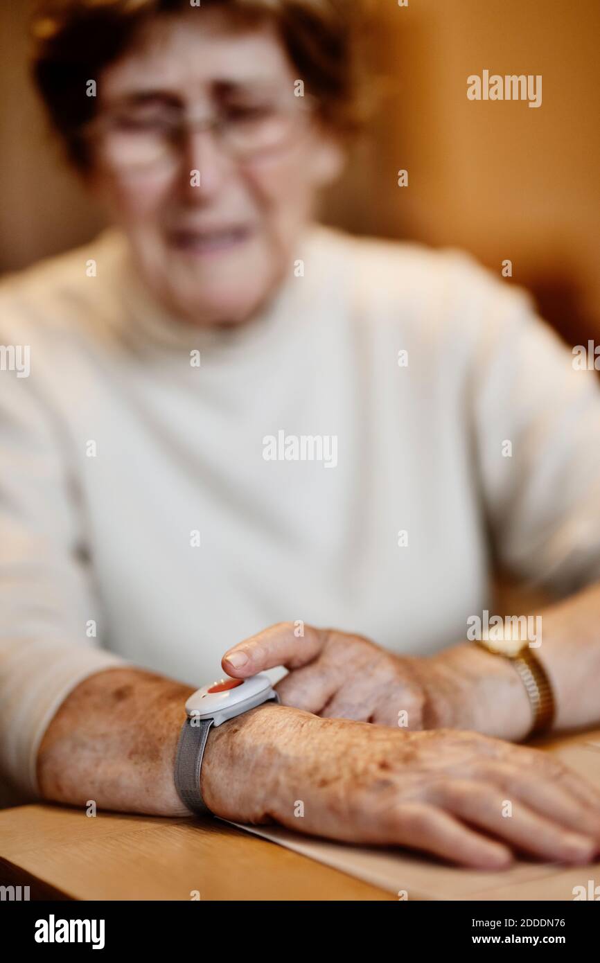 Faltig besorgt Frau drücken Nottaster am Handgelenk über Tisch Zu Hause Stockfoto