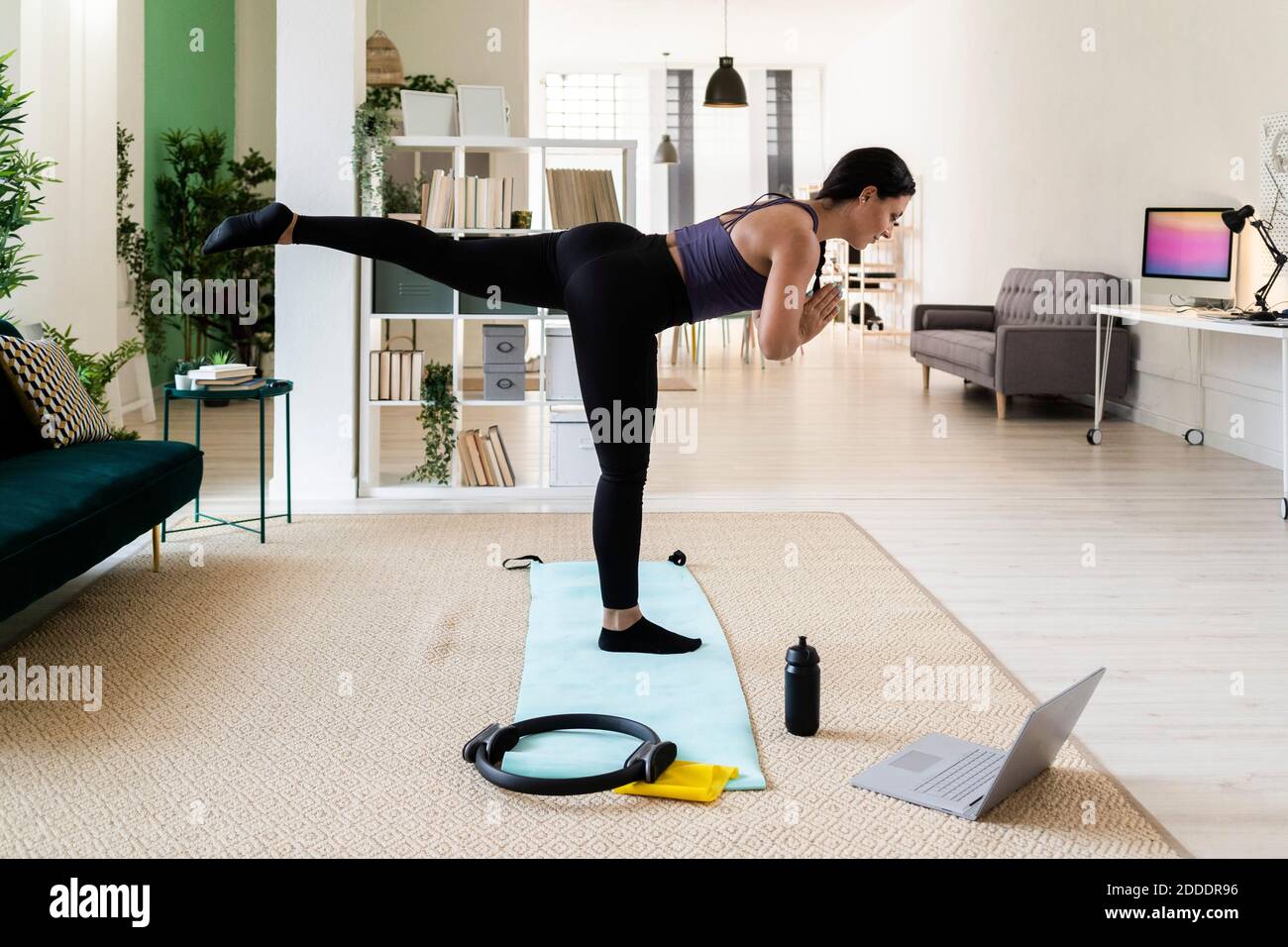 Junge Sportlerin mit einem Bein im Stehen Matte zu Hause Stockfoto